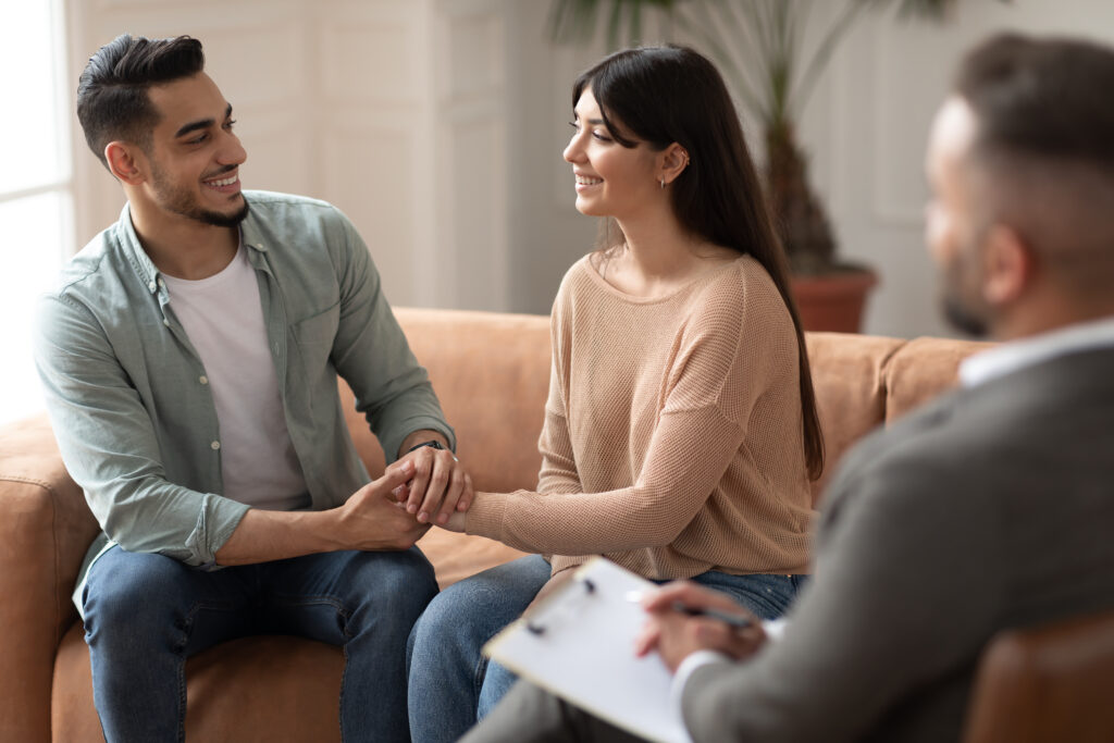 Happy couple talking at therapy session with male therapist