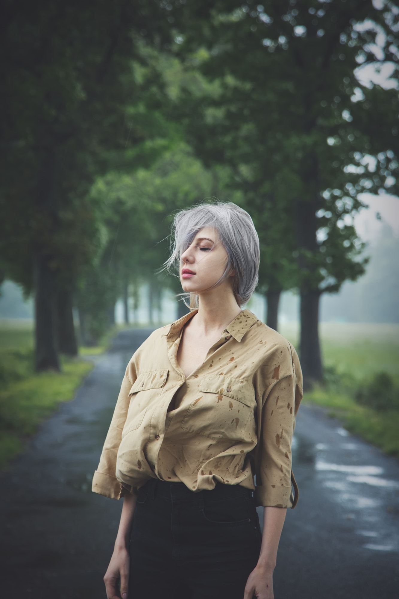 Blonde girl in depression at countryside road in rainy day