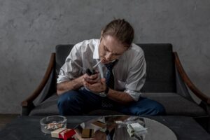 businessman with drug addiction smoking cigarette above table with various drugs